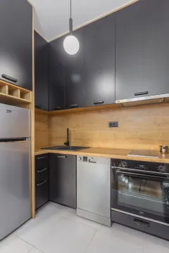 Moderna kuhinja sa crnim elementima i drvenim radnim dijelom. - image 3