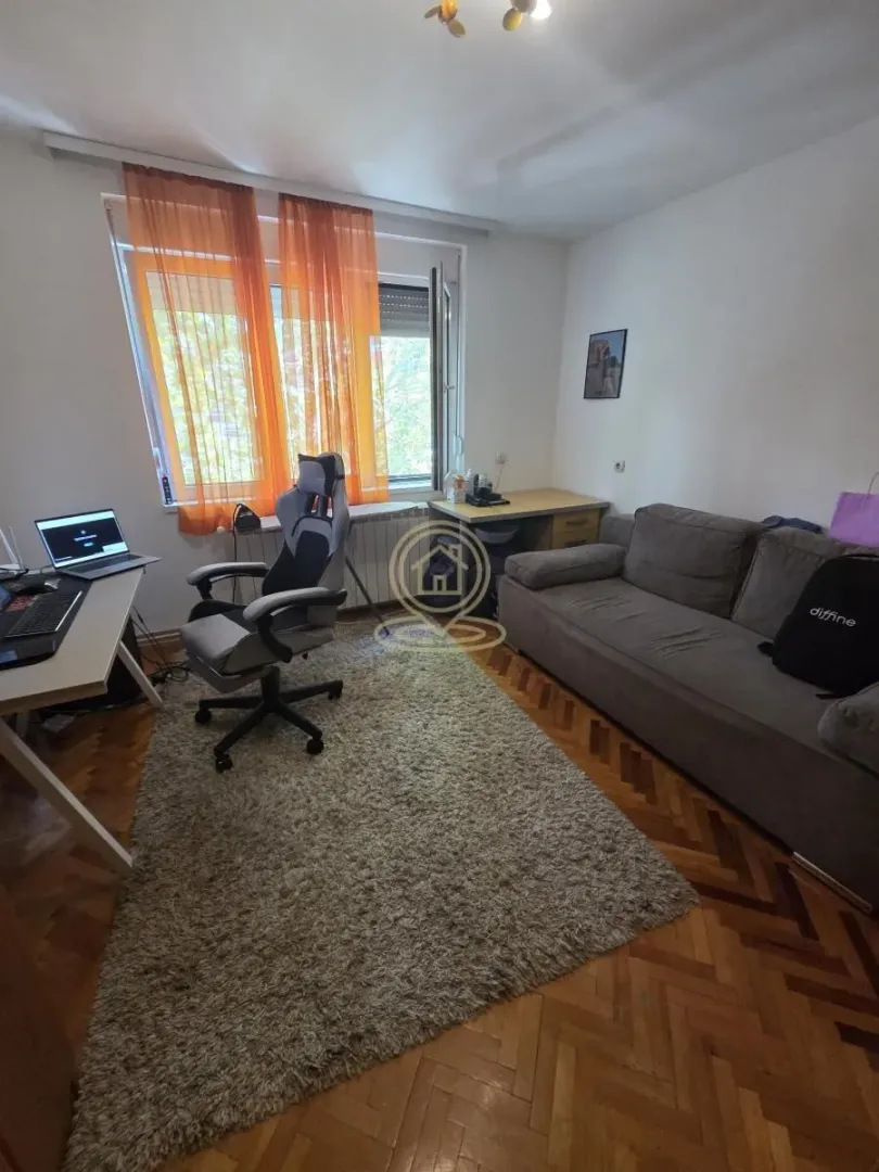 Dnevna soba sa garniturom, radnim stolom i tepihom.