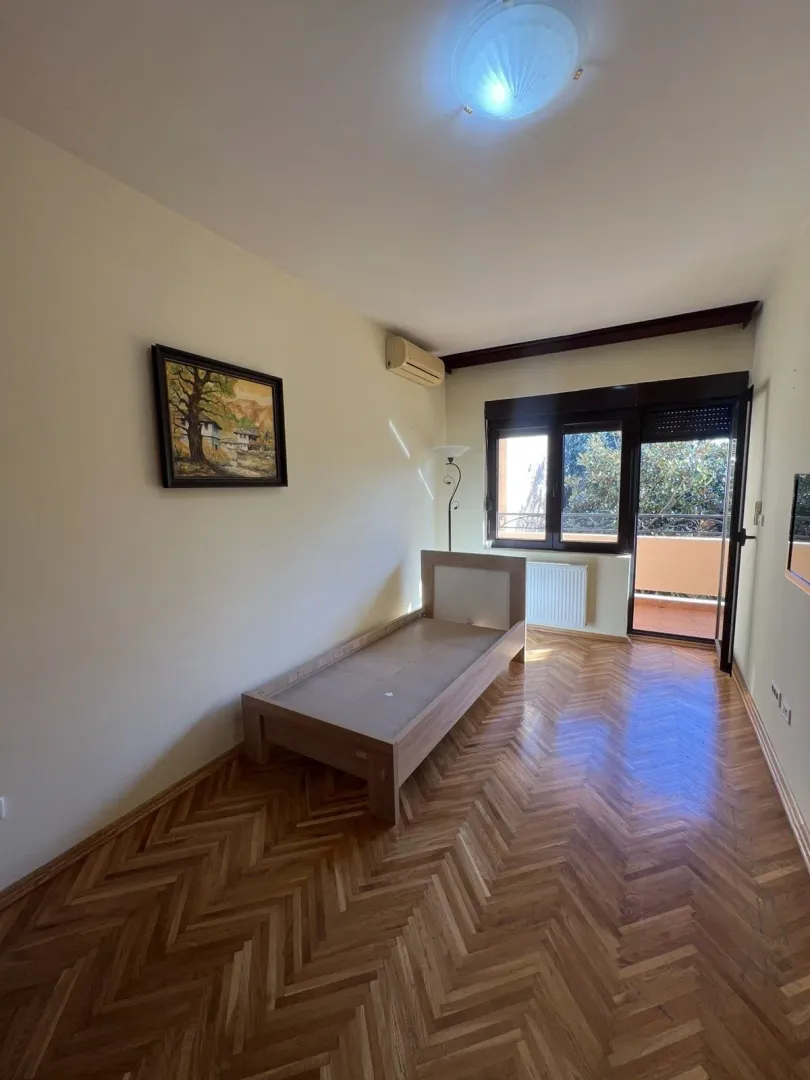 Bright bedroom with a wooden bed frame, parquet flooring, and balcony access.