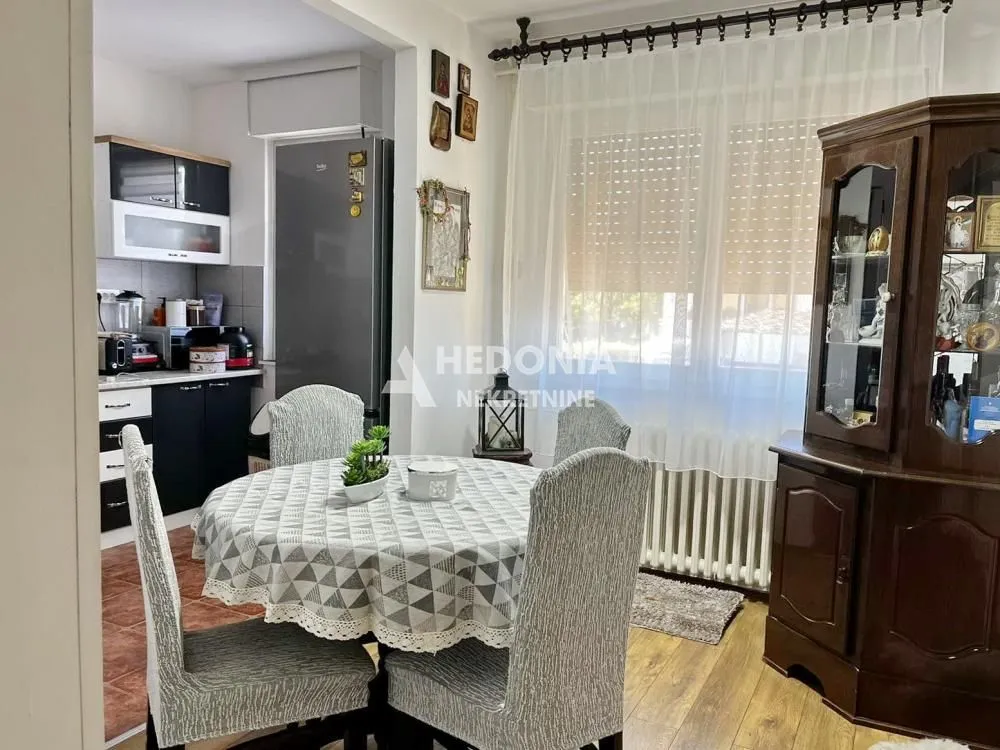 Trpezarija sa stolom i stolicama, sa pogledom na kuhinju.
