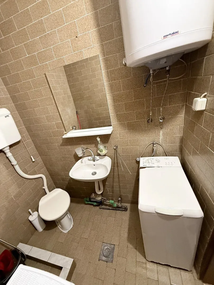 Manje kupatilo sa tuš kabinom, umivaonikom, WC šoljom i veš mašinom.