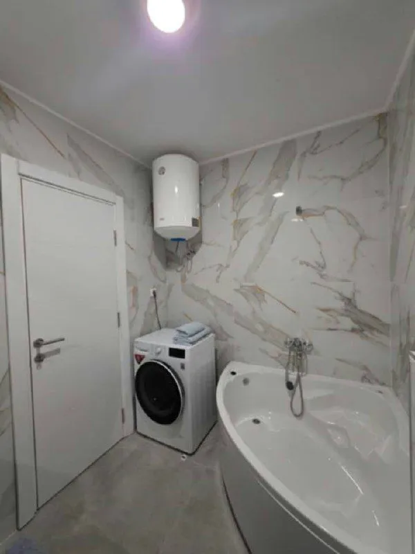 Modern bathroom with a corner bathtub, washing machine, and water heater.