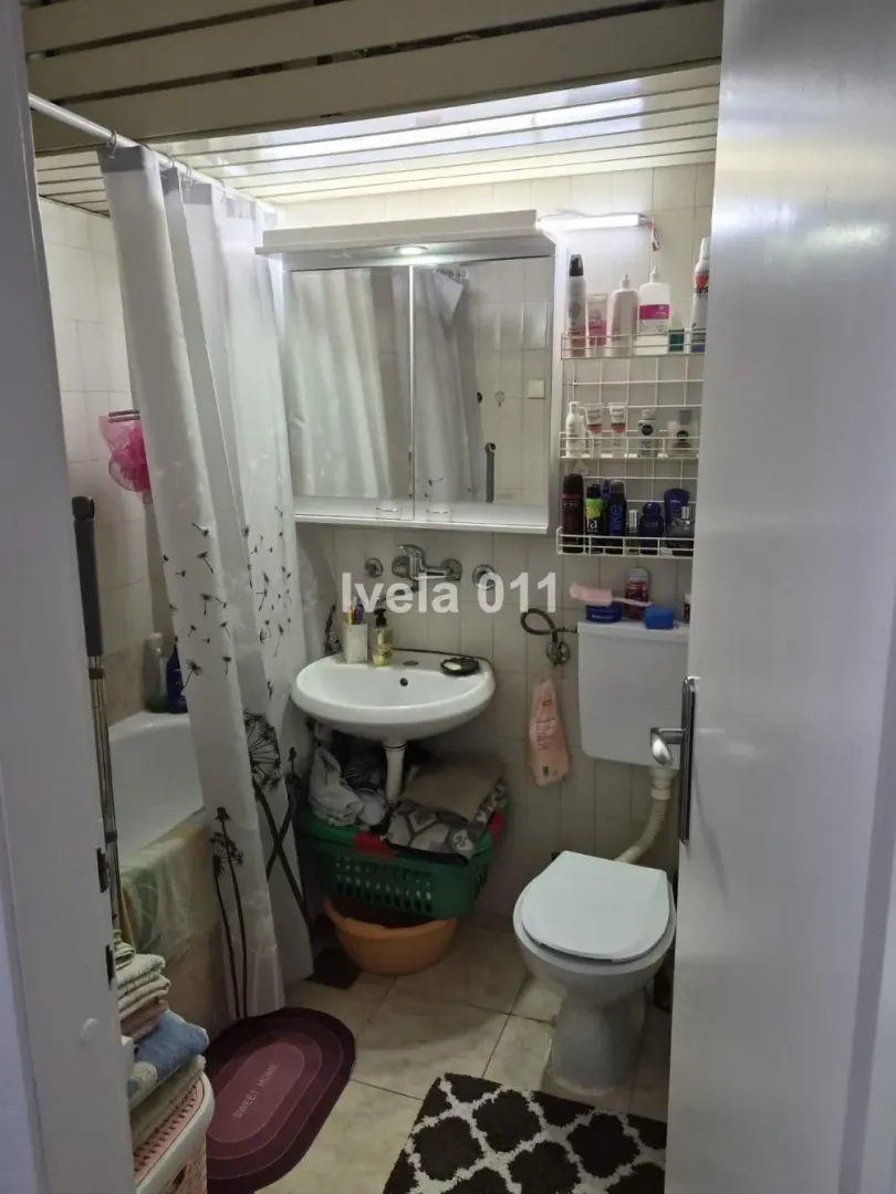 Manje kupatilo sa kadom, umivaonikom, wc šoljom i ogledalom sa ormarićem.