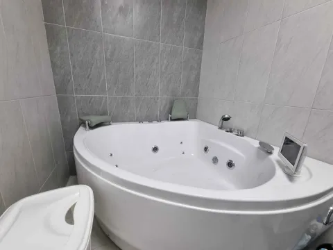 Kupatilo sa ugaonom hidromasažnom kadom i sivim pločicama. - image 8