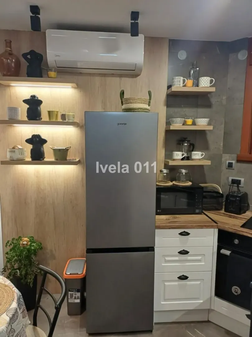 Modern kitchen with a refrigerator, shelves, and built-in units.
