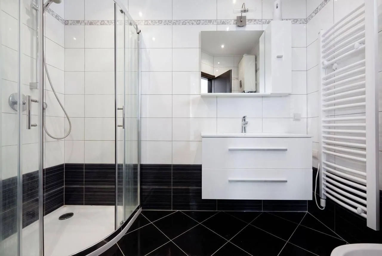 Modern and neatly arranged bathroom with a shower cabin and a white washbasin.