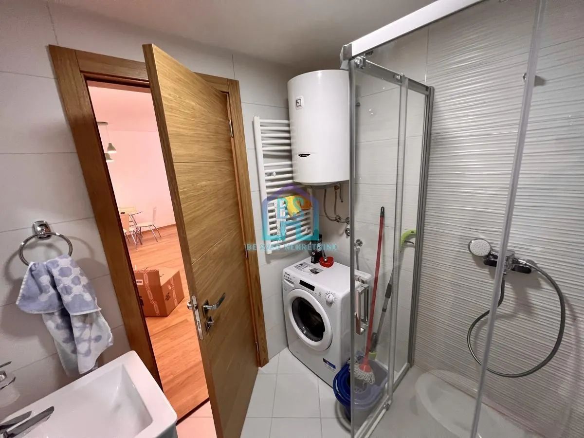 Bathroom with a shower cabin, washbasin, and washing machine.