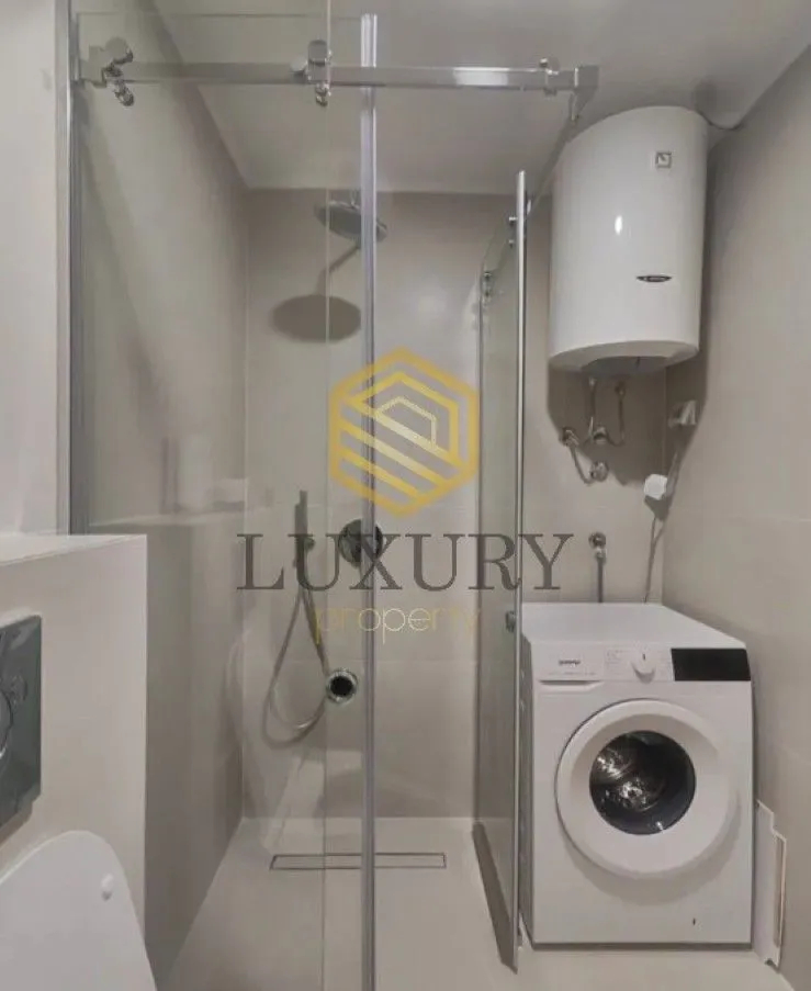 Modern equipped bathroom with a shower cabin and washing machine.