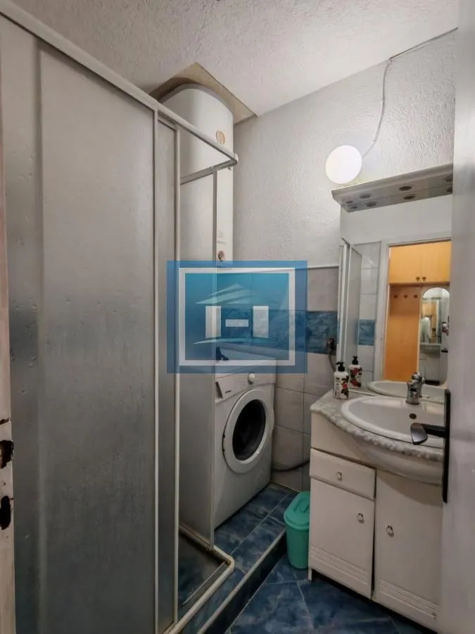Smaller bathroom with a shower cabin, washbasin, and washing machine.