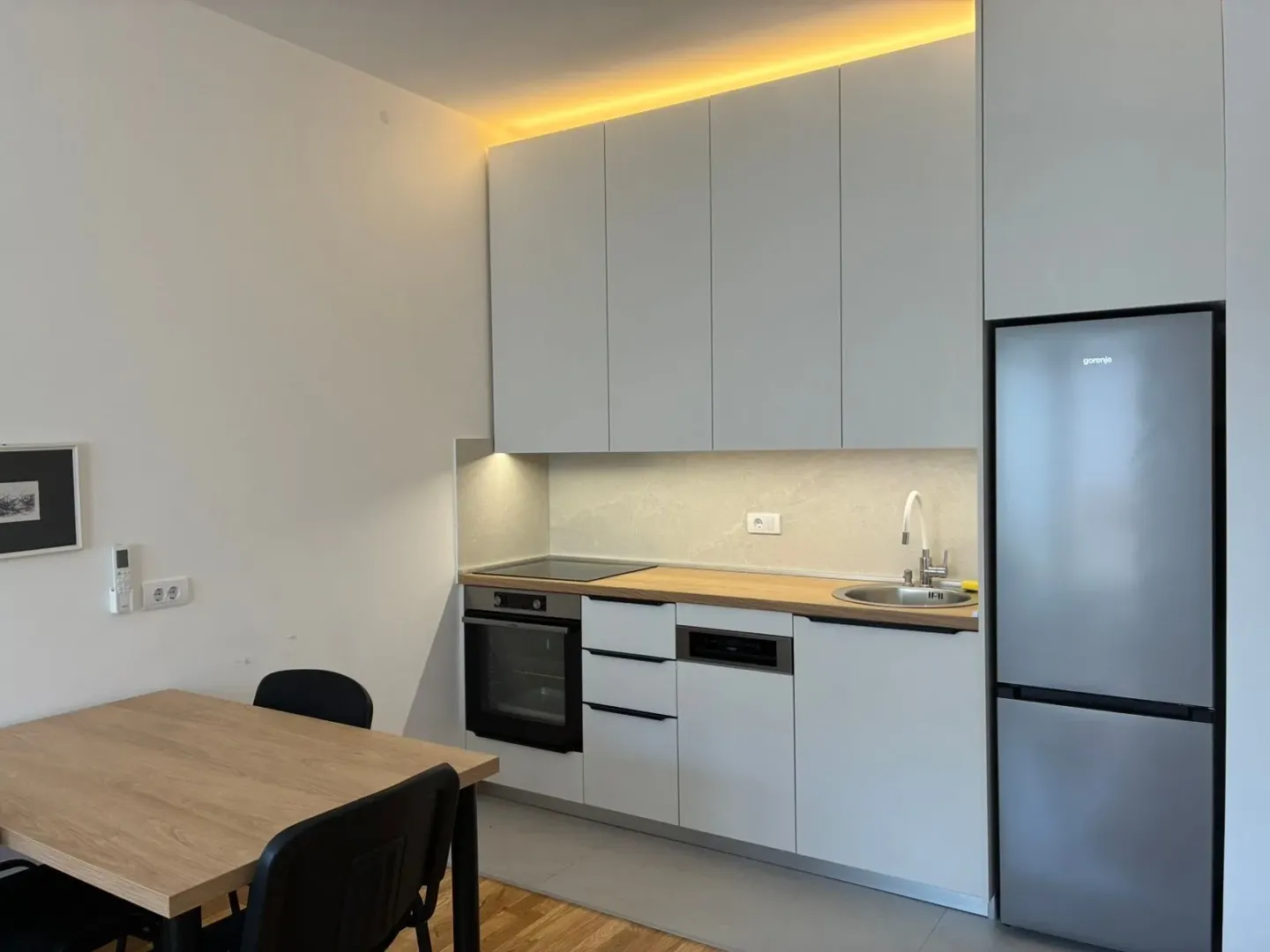 Modern kitchen with white cabinetry, built-in appliances, and a dining table.
