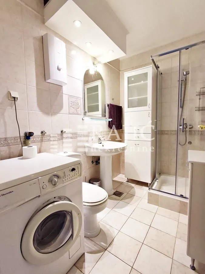 Bathroom equipped with sanitary fixtures, a shower cabin, and a washing machine.