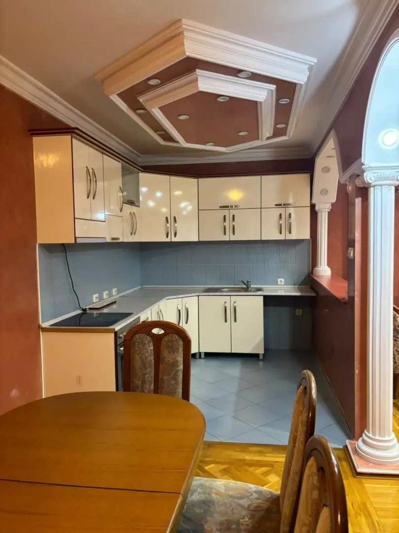 Kitchen with dining area equipped with light-colored cabinets and a decorative ceiling.