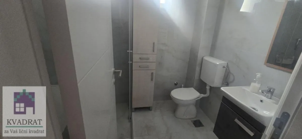 Modernly equipped bathroom with a washbasin, toilet, and cabinet.