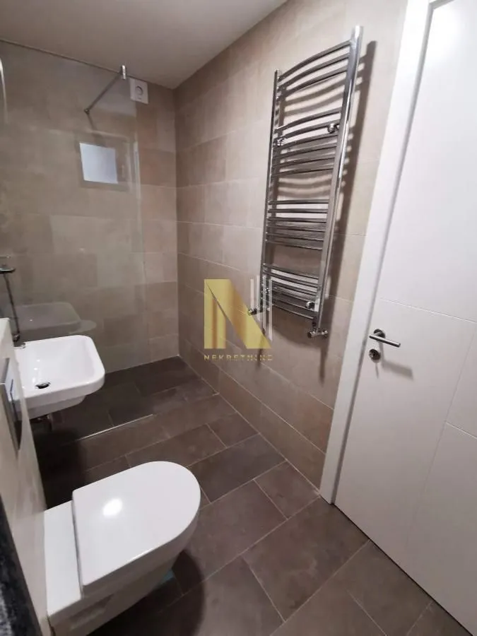 Savremeno opremljeno kupatilo sa tuš kabinom, umivaonikom i WC šoljom.