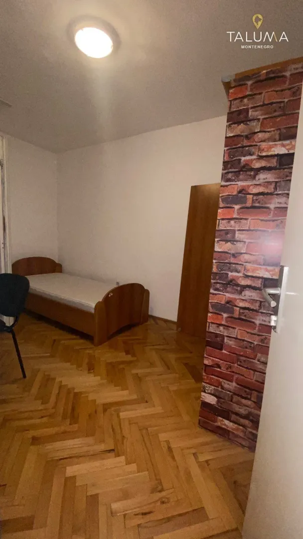 Smaller bedroom with a wooden bed and parquet flooring.