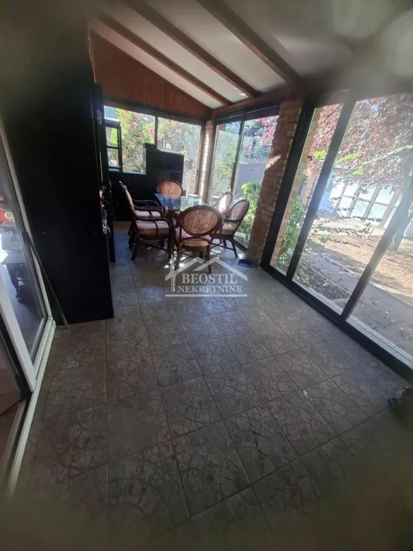 Enclosed terrace with a dining table and chairs, and a view of the yard.