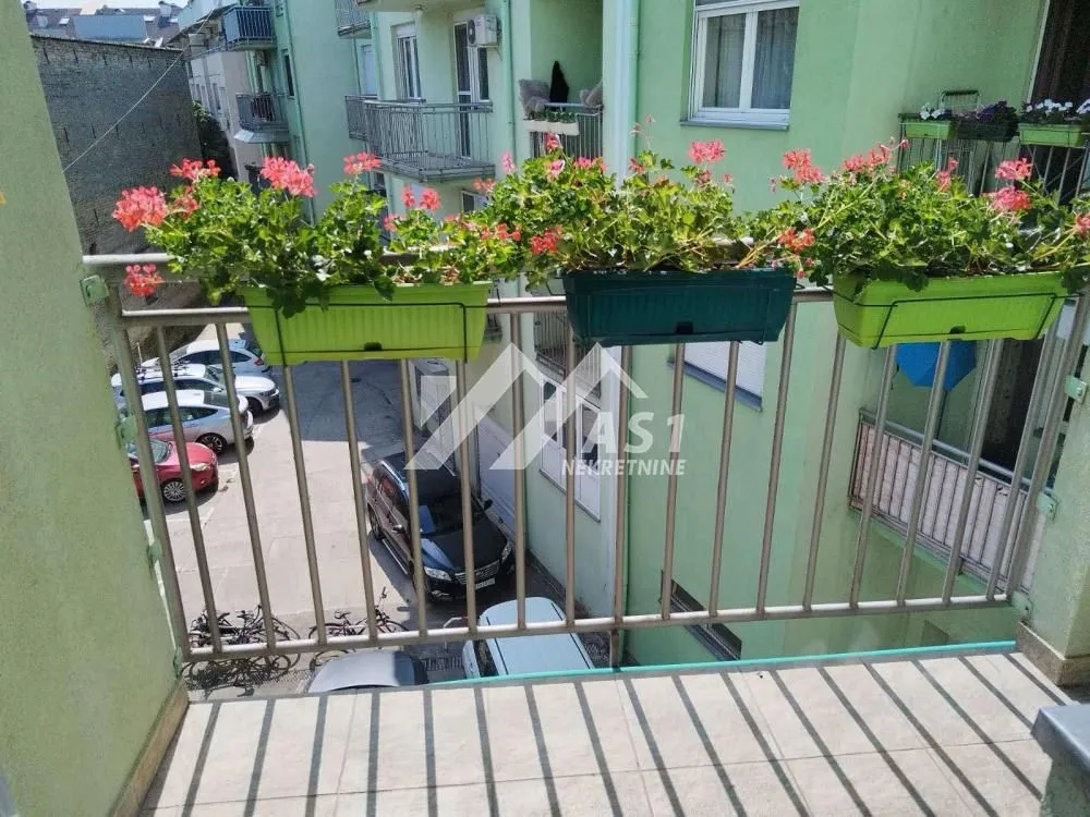 Balkon sa ogradom i žardinjerama sa cvećem.