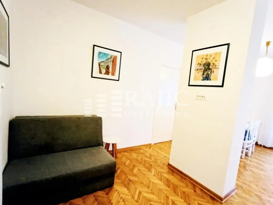 Smaller living room with a sofa and parquet flooring.