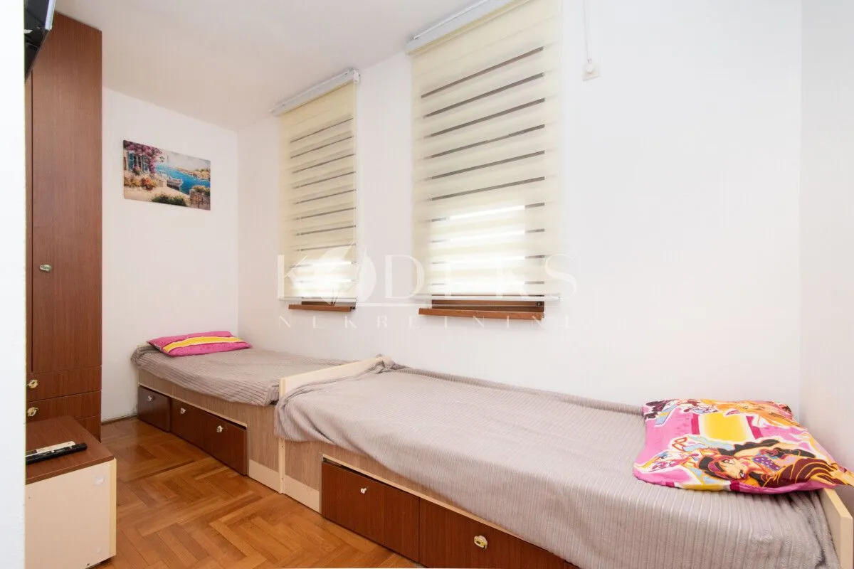 Children's bedroom with two single beds and wooden flooring.