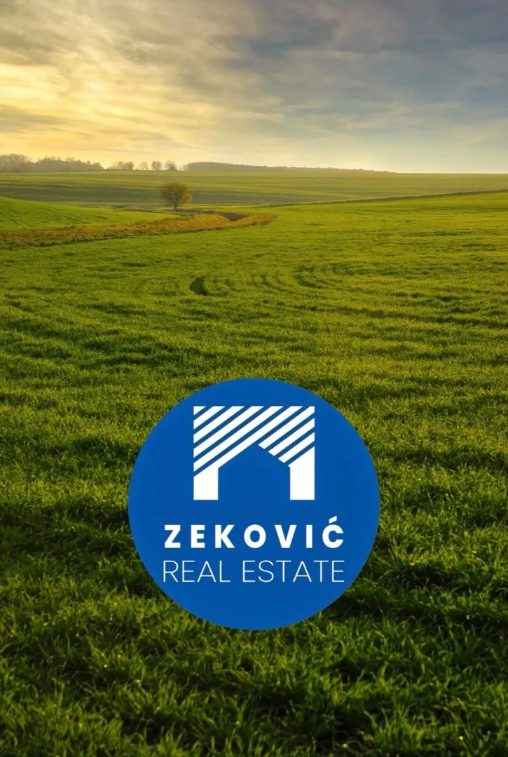 Pogled na zelenu poljanu i pejzaž sa logotipom agencije u prvom planu.