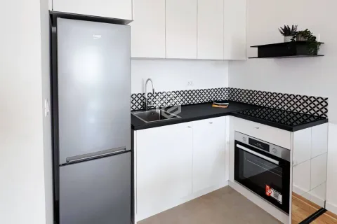 Small modern kitchen with white cabinets, black countertop, and refrigerator. - image 8
