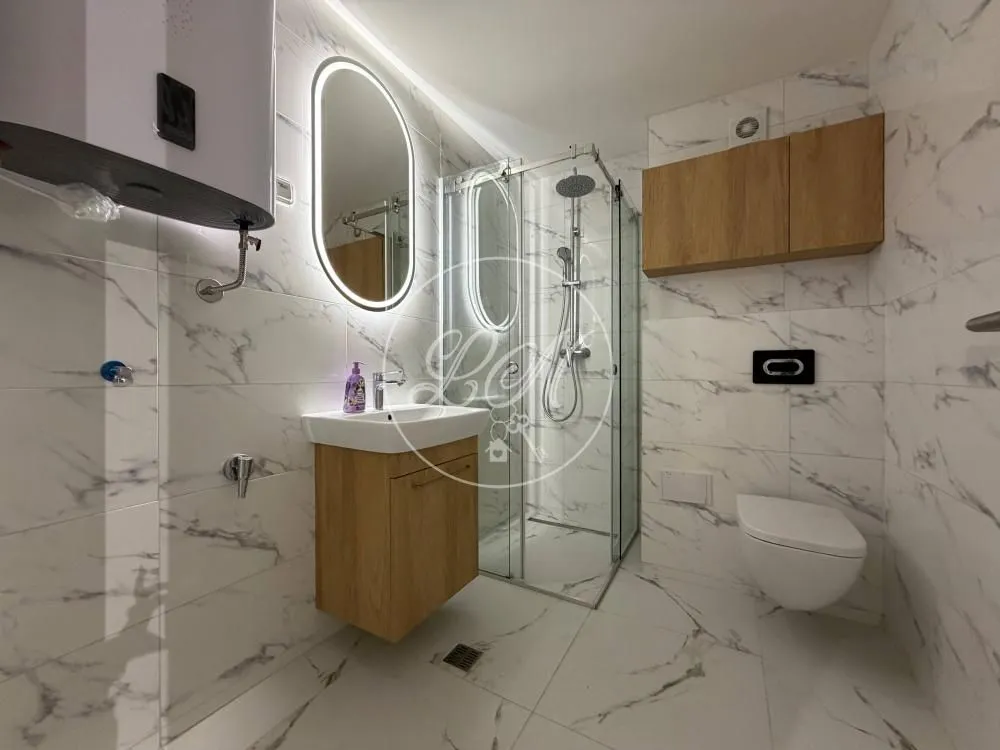 Modern bathroom with a shower cabin, washbasin, and wall-mounted toilet.