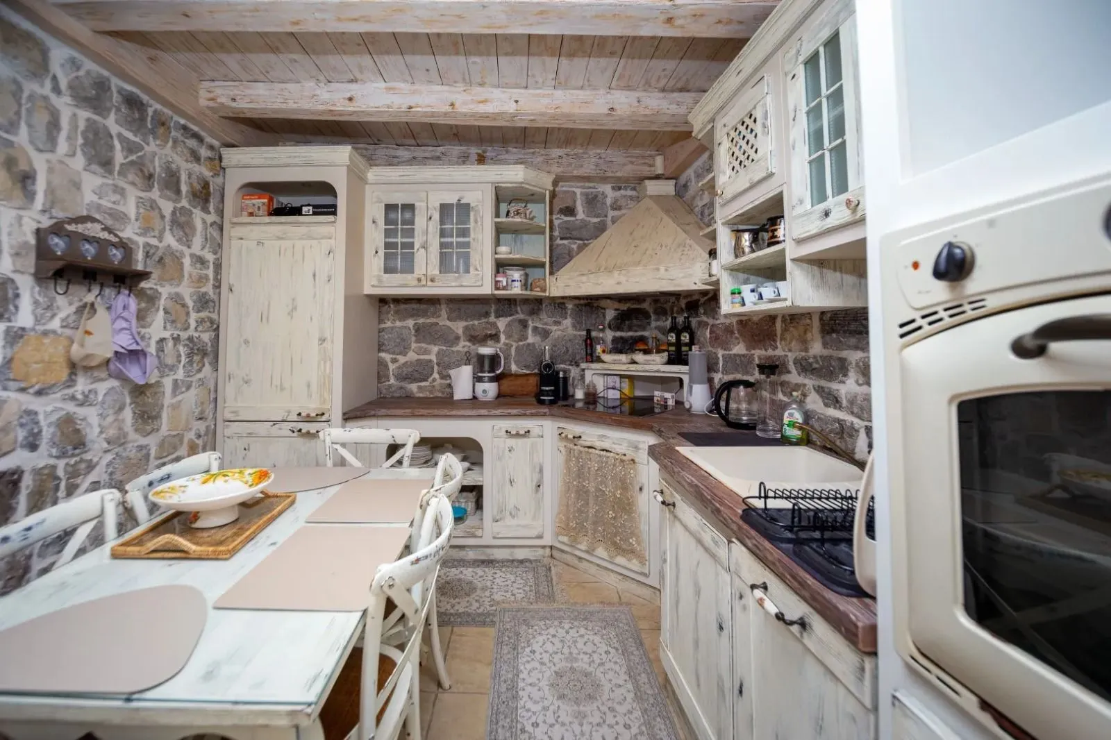 Rustic kitchen with wooden elements, stone walls, and a dining table.