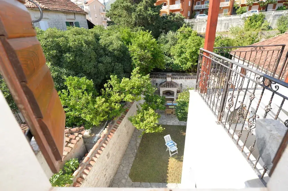 View from the balcony overlooking the courtyard with greenery and a barbecue.