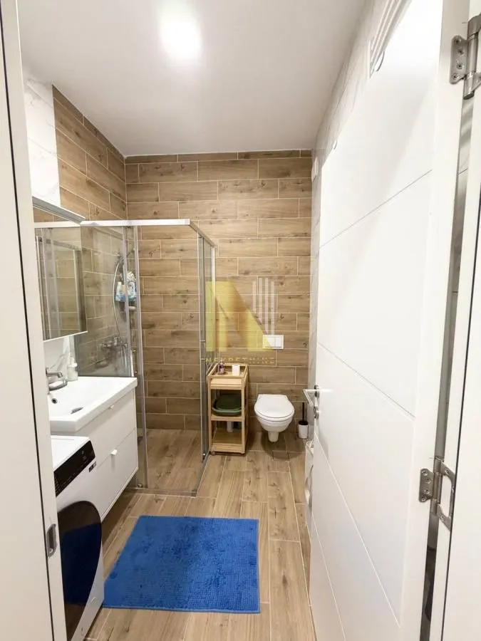 Moderno kupatilo sa tuš kabinom, umivaonikom i WC šoljom.
