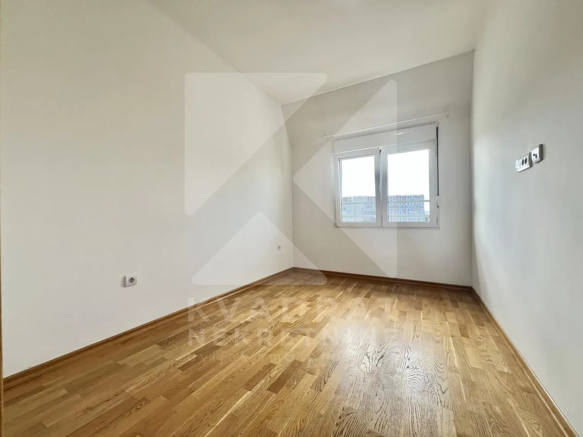 Empty bright room with hardwood flooring and a window.
