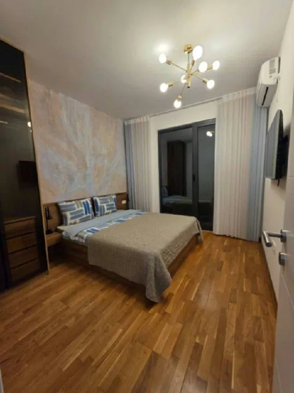 Modern bedroom with a double bed, wooden flooring, and a wardrobe.