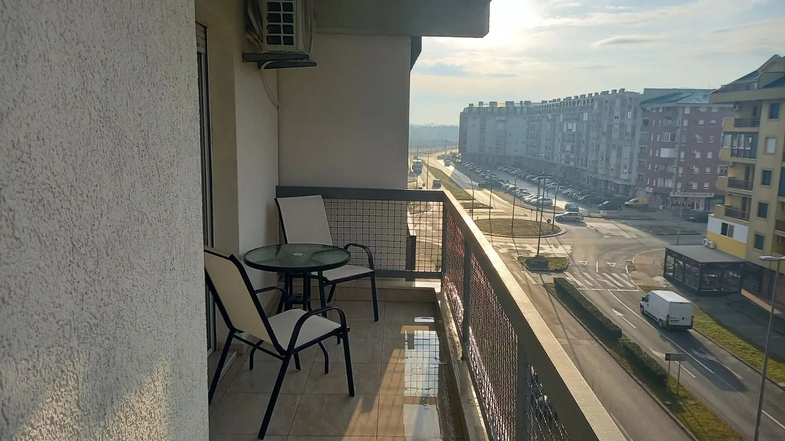 Balkon sa stolom i dvije stolice i pogledom na grad.