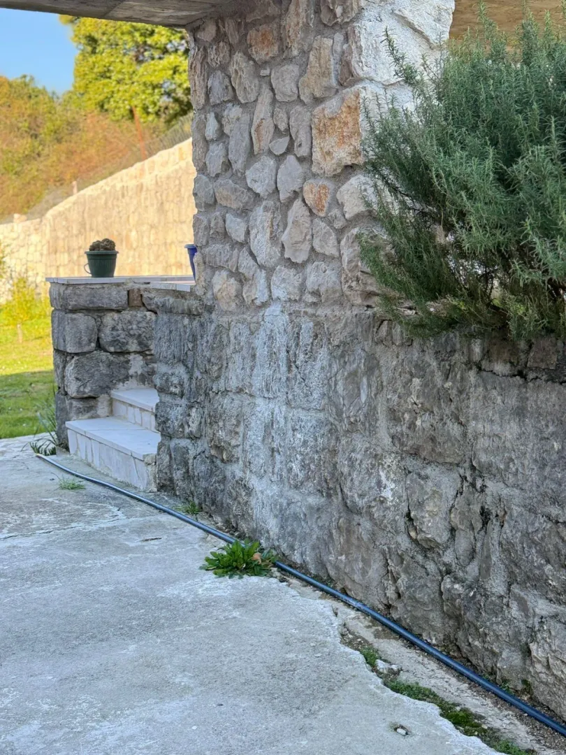 Eksterijer kuće sa kamenim zidovima i stepeništem.
