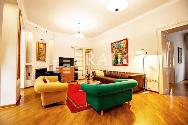 Spacious and bright living room with seating furniture and parquet flooring.