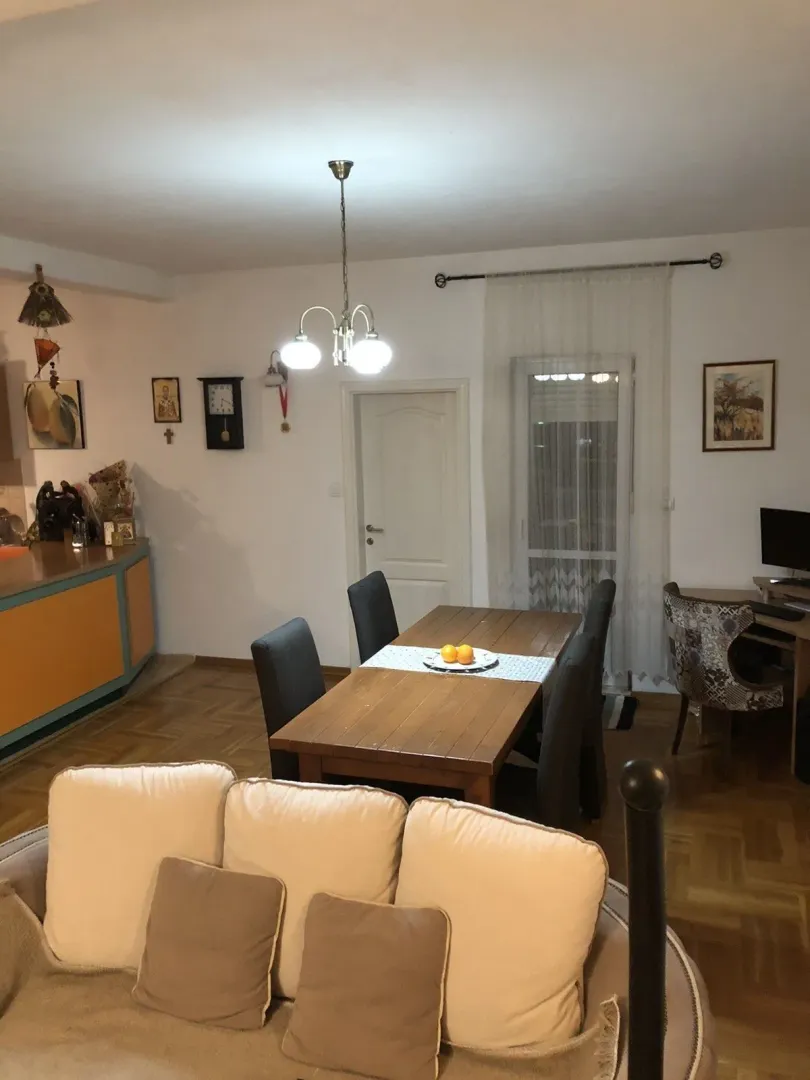 Bright living room with a dining table and parquet flooring.