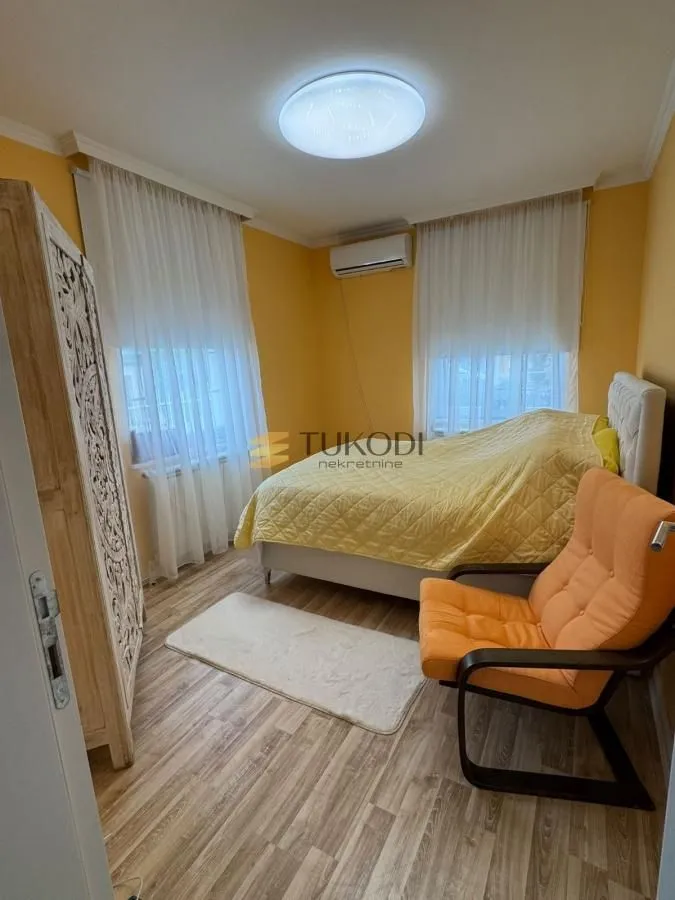 Nameštena spavaća soba sa krevetom, foteljom i garderoberom.