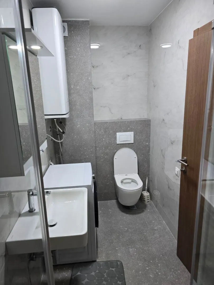Modernly equipped bathroom with a sink, toilet, and washing machine.