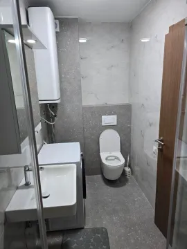 Modernly equipped bathroom with a sink, toilet, and washing machine. - image 5
