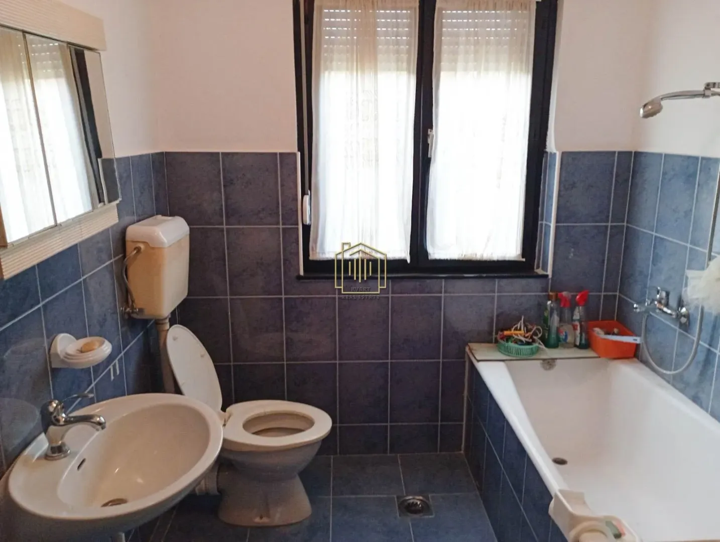 Bathroom with a bathtub, washbasin, and toilet tiled with blue tiles.
