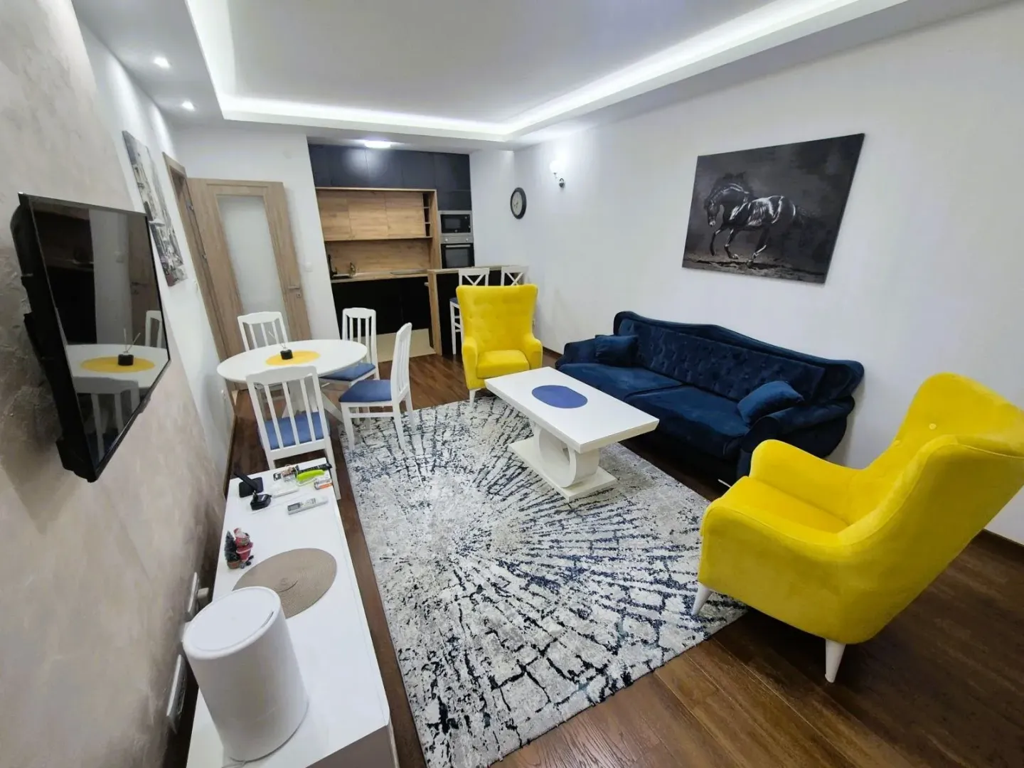 Living room with sofa set, dining area and kitchen in the background.