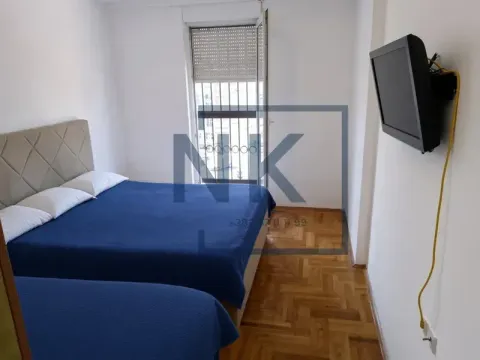 Spavaća soba sa dva kreveta i televizorom na zidu. - image 3