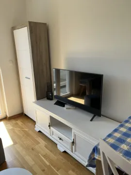 A bright section of a room featuring a TV stand and a tall wardrobe. - image 7