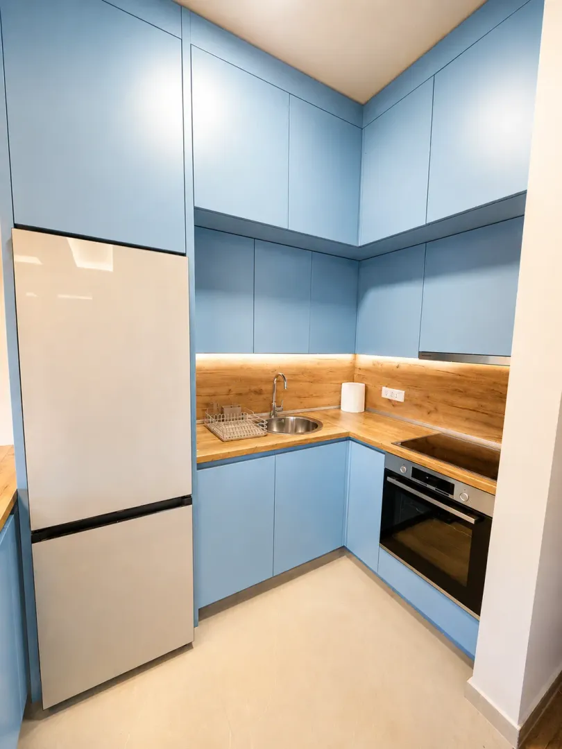 Modern kitchen with blue cabinets, wooden countertop and built-in appliances.