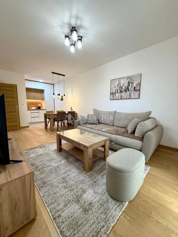 Living room with a sofa, dining area, and kitchen in the background.