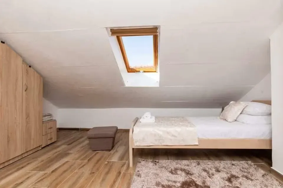 Attic bedroom with a bed, wardrobe, and skylight window.