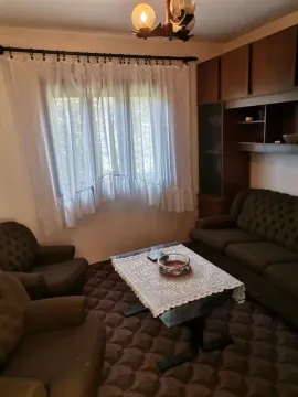 Dnevna soba sa garniturom za sedenje, stočićem i prozorom sa belim zavesama. - image 5