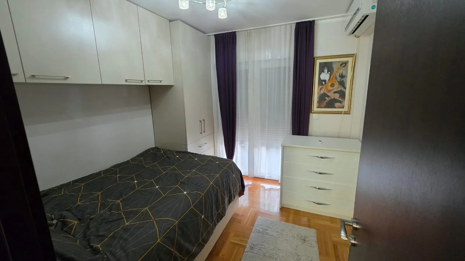 Furnished bedroom with closets, bed, and chest of drawers.
