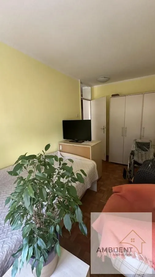 Furnished bedroom with a bed, wardrobe, and television.