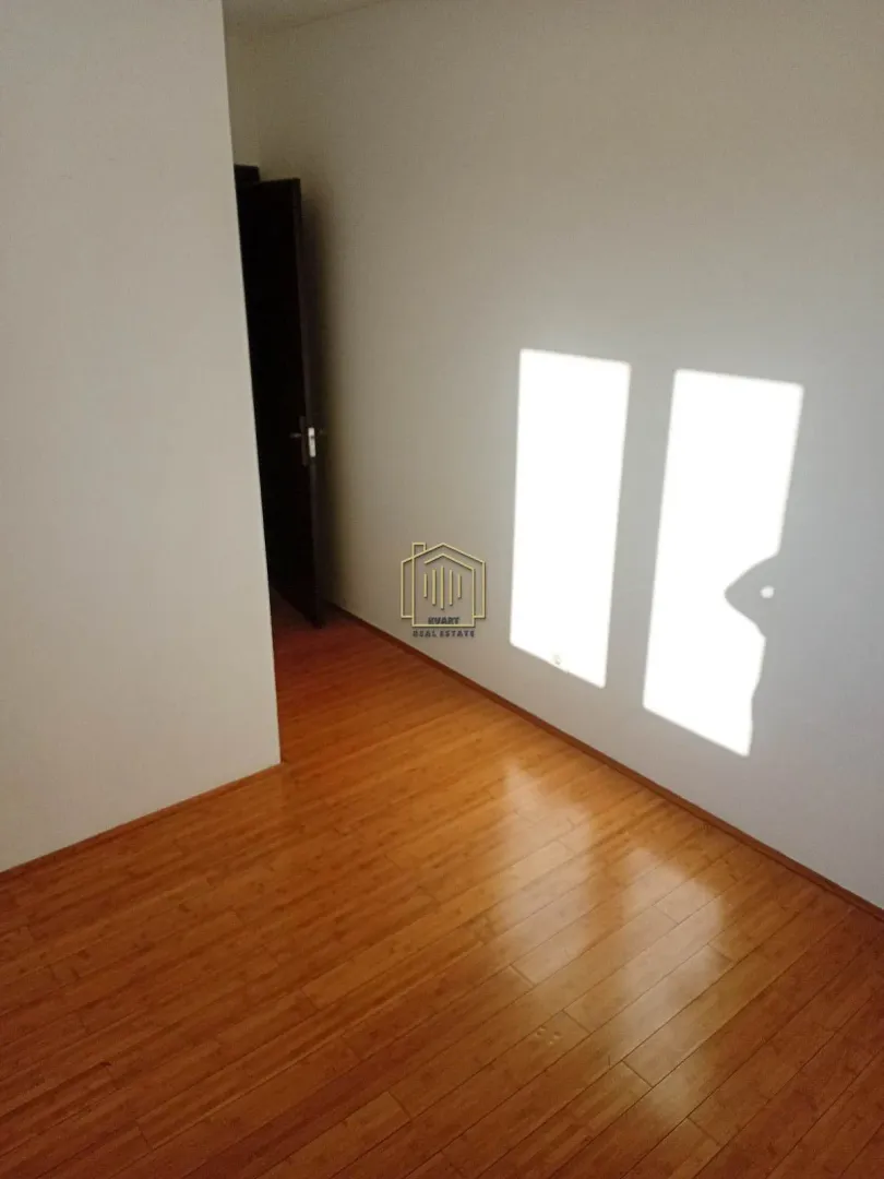 Empty room with wooden flooring and light cast on the wall.