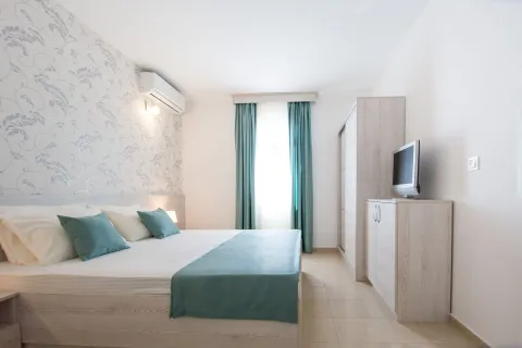 Bright bedroom with a double bed, wardrobe, and TV unit. - image 4